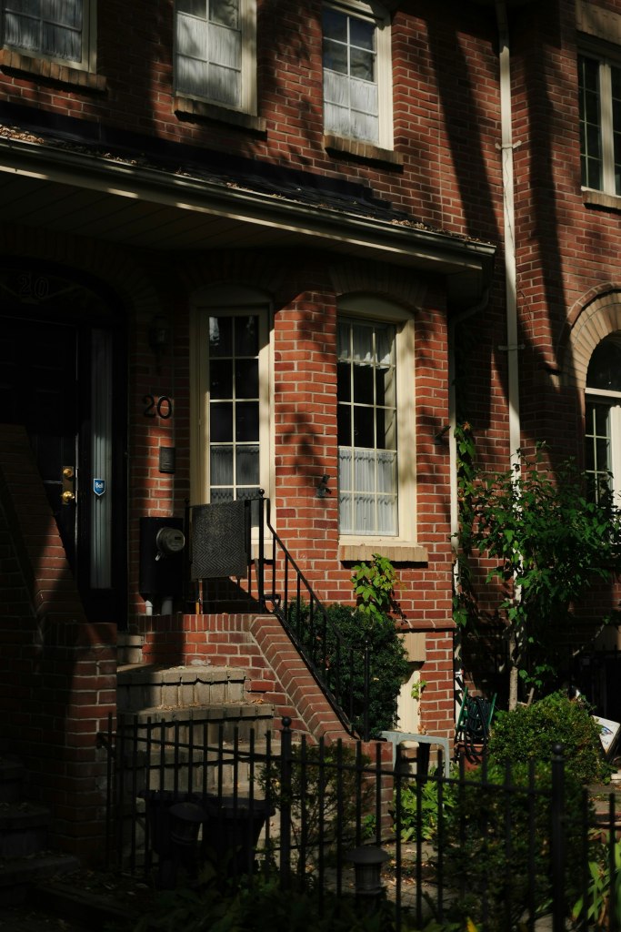 Brick row houses with white windows and front steps on a Toronto street