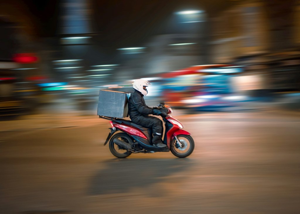 A food delivery rider on a scooter at night