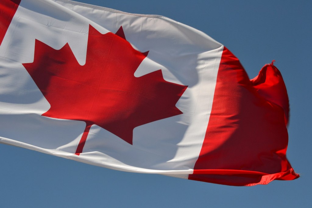 The Canadian flag flying against a clear blue sky